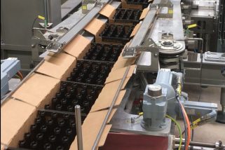 Avoiding bottle breakage: special trolley with spring assembly and customized drive chain positions cartons precisely on the pack conveyor