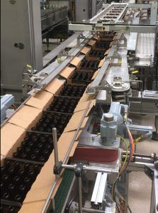 Avoiding bottle breakage: special trolley with spring assembly and customized drive chain positions cartons precisely on the pack conveyor