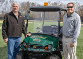 Gary Fairchild and Chad Fairchild present donation of a Cushman Hauler 1200 commercial utility vehicle to the athletics department at St. Norbert College in De Pere, Wisconsin.